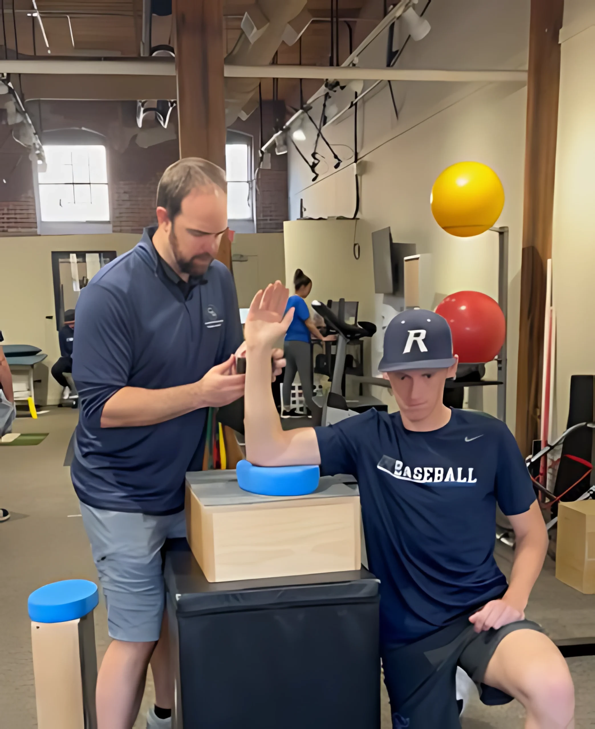 Physical therapist examining his patient's shoulder and elbow during an appointment at Complete Game Physical Therapy