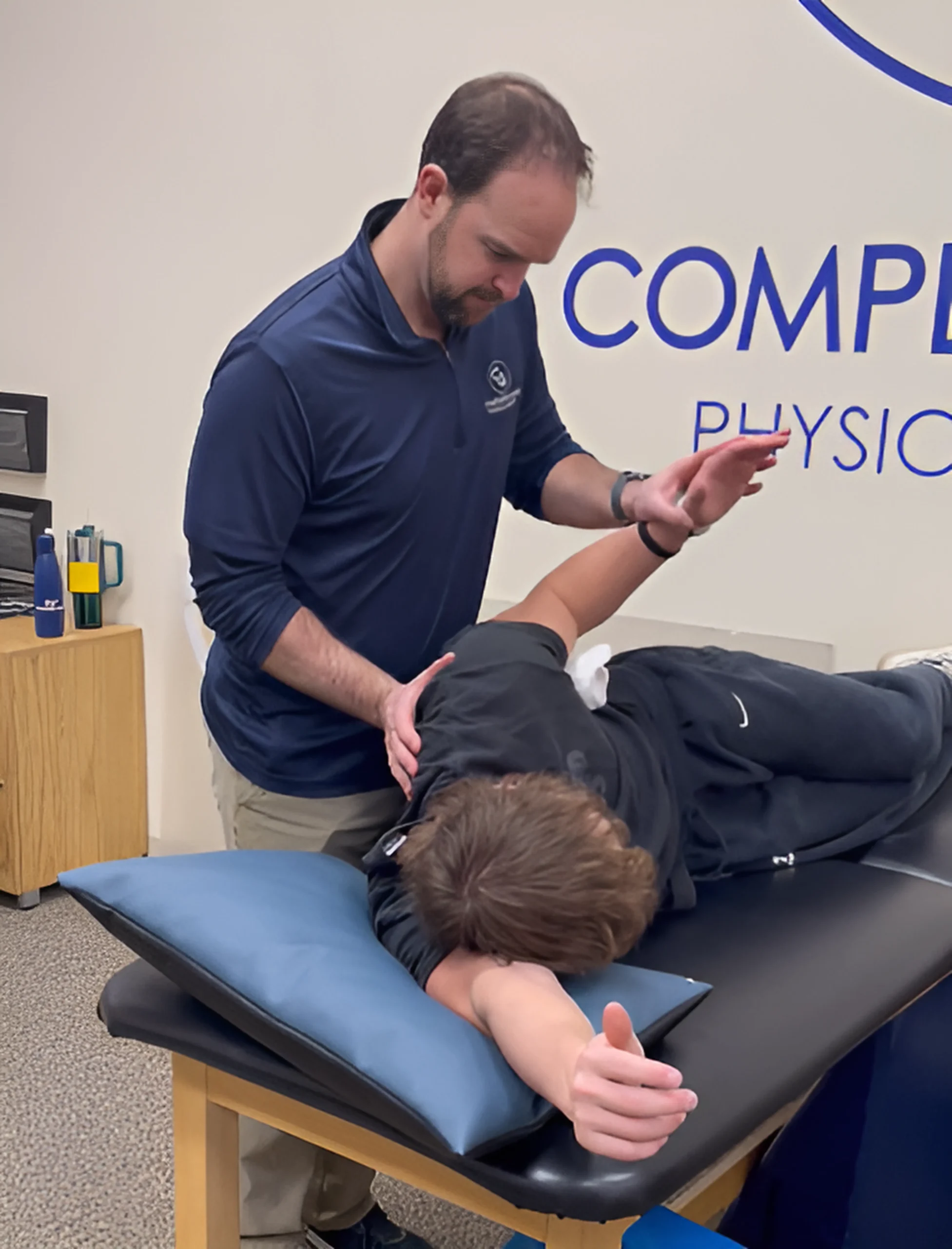 Physical Therapist at stretching and using manual therapy techniques on his patient's shoulder at Complete Game Physical Therapy